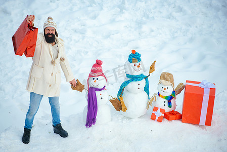 快乐的父亲在下雪的冬天散步时和雪人玩耍。