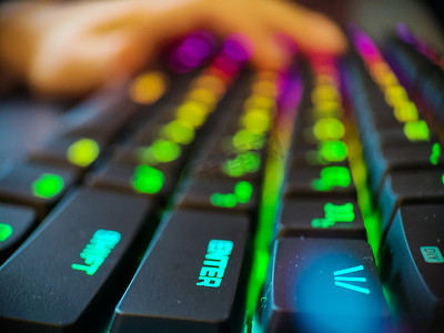带有霓虹灯背光宏的游戏玩家键盘离焦特写。