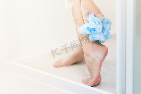 女人用沐浴海绵洗腿。