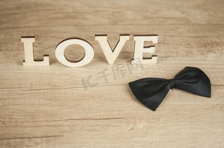 木字爱与木桌上的黑色蝴蝶领带盒。