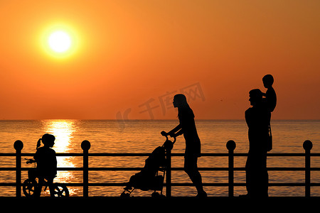 日落时，家庭在海滨长廊上