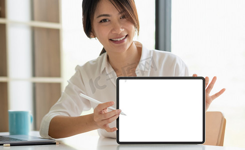 微笑美丽的亚洲女商人展示空白平板电脑显示器，带有用于标语或文本消息的复制空间区域。
