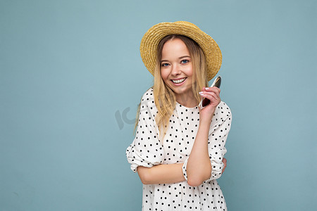 迷人的微笑的年轻金发女性穿着日常时尚的衣服和现代太阳镜隔离在彩色背景墙上看着相机