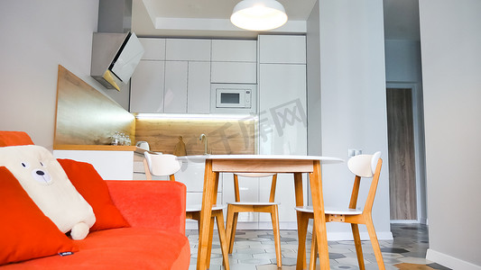 现代厨房内饰采用木质和白色元素，明亮的橙色沙发，家庭生活，家居展示室内概念。