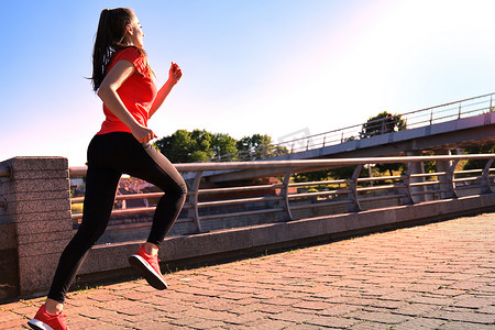 现代年轻女性穿着运动服在户外锻炼时跳跃的照片。