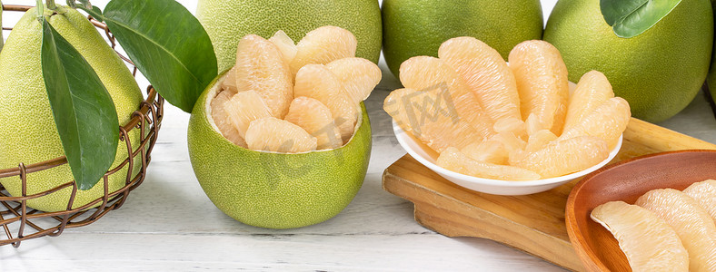 深海蜜柚摄影照片_新鲜去皮的柚子、柚子、柚子、柚子在明亮的木桌背景上。