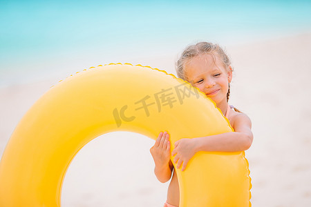 度假圈摄影照片_海滩度假时带充气橡胶圈的小女孩肖像