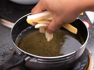 在厨房的电炉上用热油在油炸锅中炸薯条的特写。