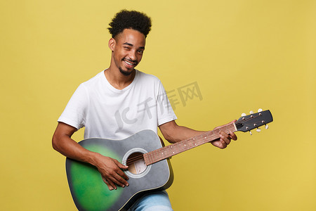 快乐的非洲裔美国音乐家在金黄色背景下用吉他合影。