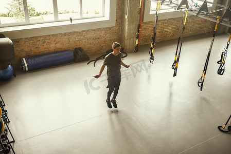 全长的年轻运动男子在健身房锻炼时正在跳绳