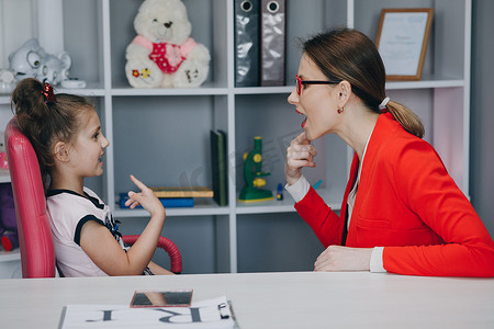 学龄前儿童女孩在与父母妈妈或语言治疗师老师的私人课程中练习发音。