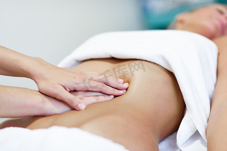 按摩女性腹部的手。治疗师对腹部施加压力。