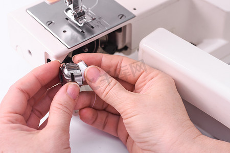 缝纫机特写摄影照片_女裁缝将线轴插入缝纫机的线轴。