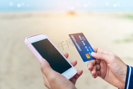 金融移动端摄影照片_妇女手持信用卡并使用移动智能手机进行网上购物或报告丢失的卡、欺诈交易。