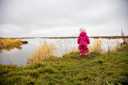 一个小孩站在湖岸上，望着远方。