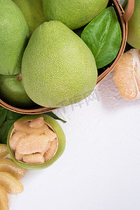 深海蜜柚摄影照片_新鲜的柚子，竹篮中的葡萄柚，绿叶明亮的白色背景。