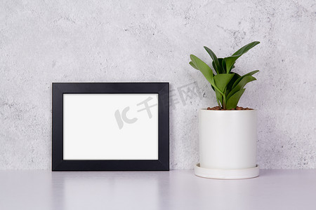 黑色黑色边框摄影照片_水平模型黑色框架和家中桌面盆栽植物、用于演示的模型海报、画廊照片和图片的设计、边框模板和广告装饰。