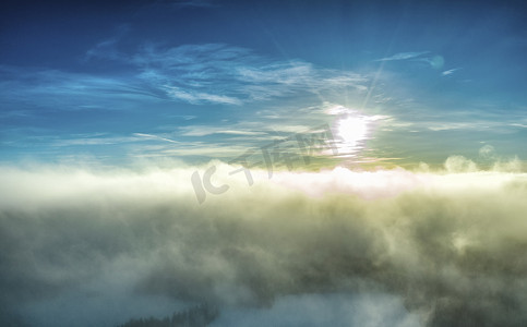 日落前冬日的空中全景照片，在寒冷的亚北极云层之上，非常蓬松的浅云被太阳光线着色，并从下面被霜雾和空气变暗。