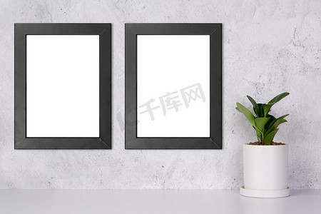 黑色黑色边框摄影照片_墙上的黑色框架模型和家里桌面上的盆栽植物，桌面上展示的模型海报，画廊照片和图片的设计，广告的边框模板。