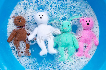 将兔子娃娃和小熊玩具浸泡在洗衣粉水里