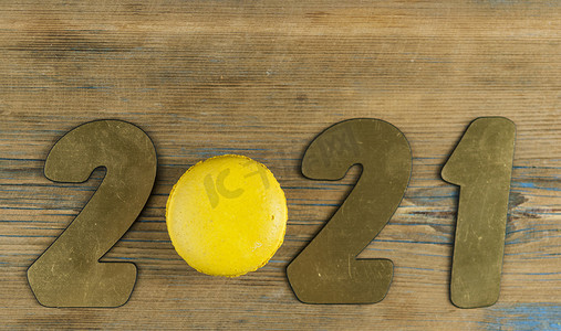 马卡龙背景板摄影照片_2021 号的顶视图，即将到来的新年的象征，质朴的木质背景上色彩缤纷的杏仁饼。