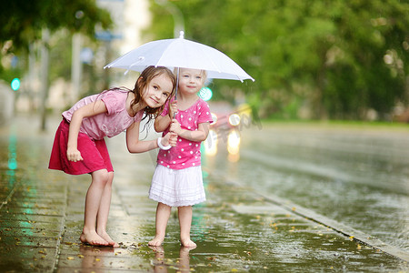 两个可爱的小姐妹在雨中玩得开心