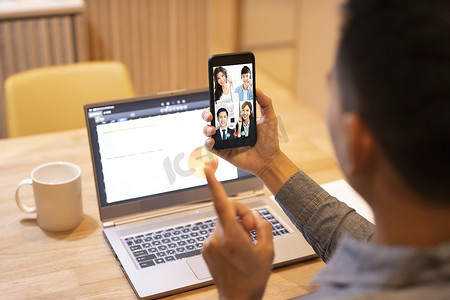在家工作并使用带视频会议的智能手机的年轻人