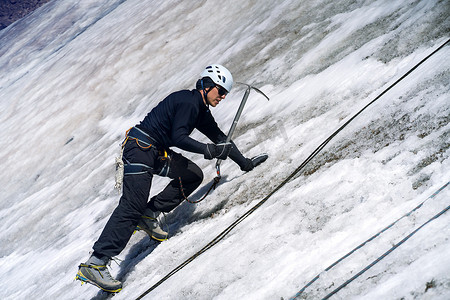 冰川运动摄影照片_冰川上拿着冰镐的男人。