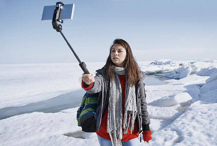 女旅行者在冰冷的户外使用独脚架拍摄自拍图片