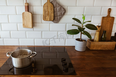 现代白色厨房中电磁炉上的烹饪锅和平底锅中的沸水