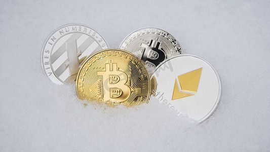 莱特币、比特币和以太坊加密货币在雪地上。