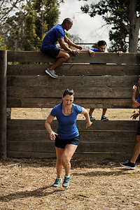 女人跑步，而教练协助男人爬木墙