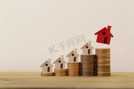 在成堆的硬币上安排红色优秀的小房子或房屋，房地产投资房地产/房屋贷款/资产再融资概念：描述房主或借款人将财产变成现金。