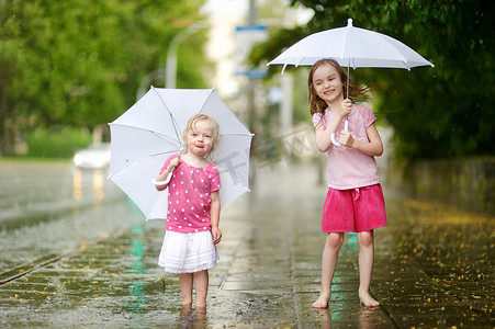 两个可爱的小姐妹在雨中玩得开心