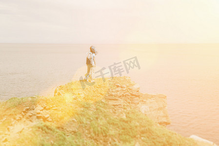 夏天，背着背包的徒步旅行者年轻女子站在山峰上欣赏海景