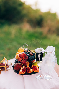 彩绘装饰摄影照片_一张彩绘的桌子上有一个书柜，里面有水果和新娘和新郎西装的香槟酒杯。