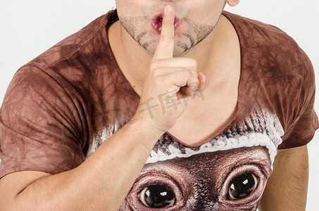 请安静摄影照片_手指放在嘴唇上，男人打着手势，请保持安静的概念。