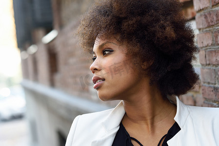 城市摄影照片_城市背景中留着非洲发型的年轻黑人女性