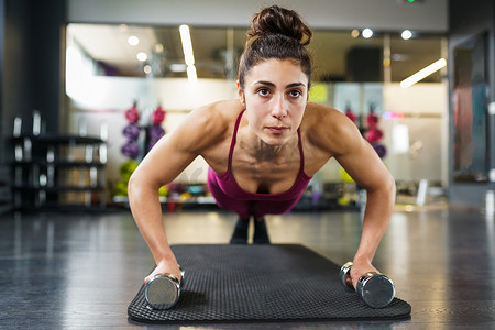 在健身锻炼中用哑铃做俯卧撑运动的女性