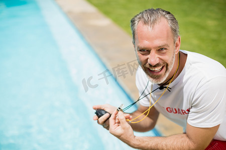游泳教练在泳池边拿着秒表的画像