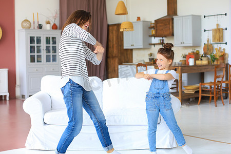 性格开朗的母亲带着小女儿在家里的客厅里唱着最喜欢的歌曲跳舞。