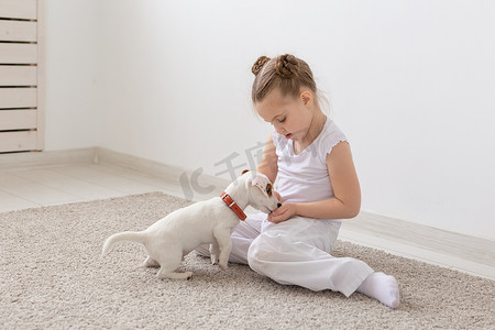 儿童、宠物和动物概念 — 穿着睡衣的小女孩在地板上与杰克罗素梗小狗玩耍