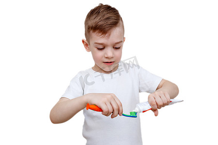 穿着白色T恤的小男孩在刷子上挤牙膏。
