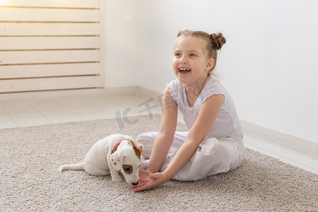 人、儿童和宠物的概念 — 小女孩和可爱的小狗坐在地板上玩耍