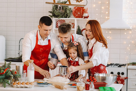 圣诞一家人摄影照片_一家人站在圣诞厨房里准备制作饼干的面团