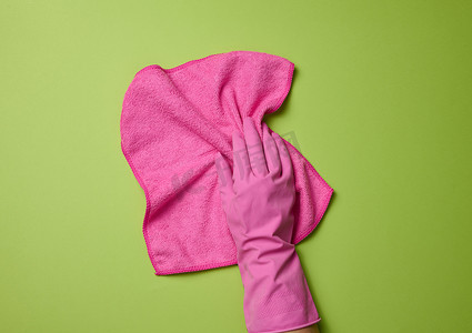 戴着粉色橡胶手套的手握着一块软抹布，用于清洁白色背景上的表面