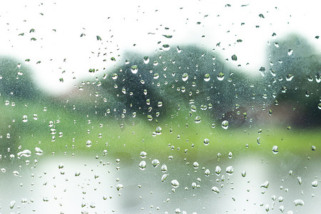 雨滴落在玻璃窗背景上。