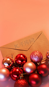 圣诞节粉色摄影照片_牛皮纸信封，粉色背景上有圣诞红色和粉色球