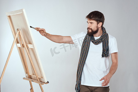 男性艺术家在画架艺术生活方式浅色背景上绘画