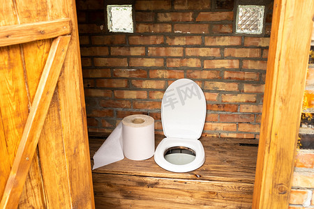 一个简单的乡村厕所，有一大卷卫生纸。厕所里有大卷卫生纸
